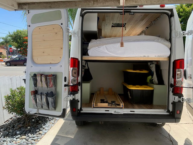 Open rv rental rear reveals bed, organized storage bins & door pockets. Ideal for van life adventures. — photo 5