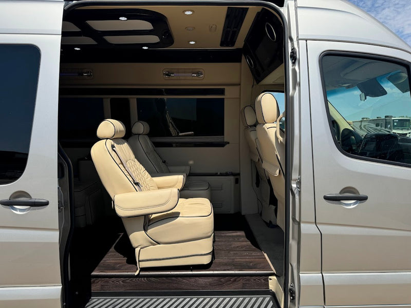 Luxury **rv rental** van interior with cream leather captain's chairs, wood floor, and custom overhead lighting. — photo 6