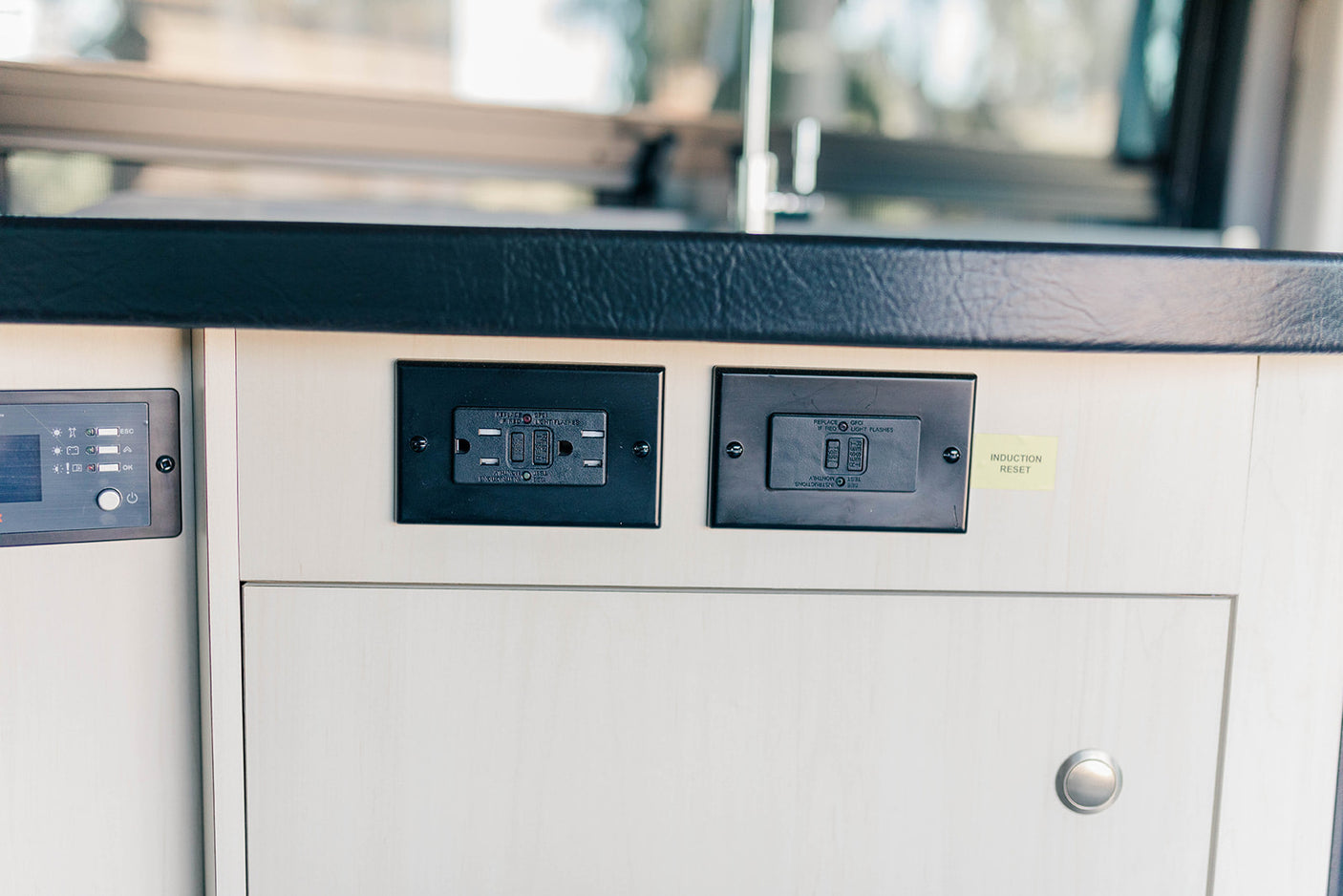 RV rental interior shows GFCI outlets, a control panel, and an "Induction Reset" note on light wood cabinetry.
