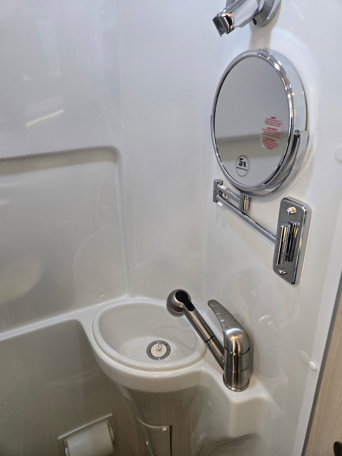 Compact RV rental bathroom with a sink, pull-out faucet, magnifying mirror, and integrated toilet paper holder, ideal for travel. — photo 19