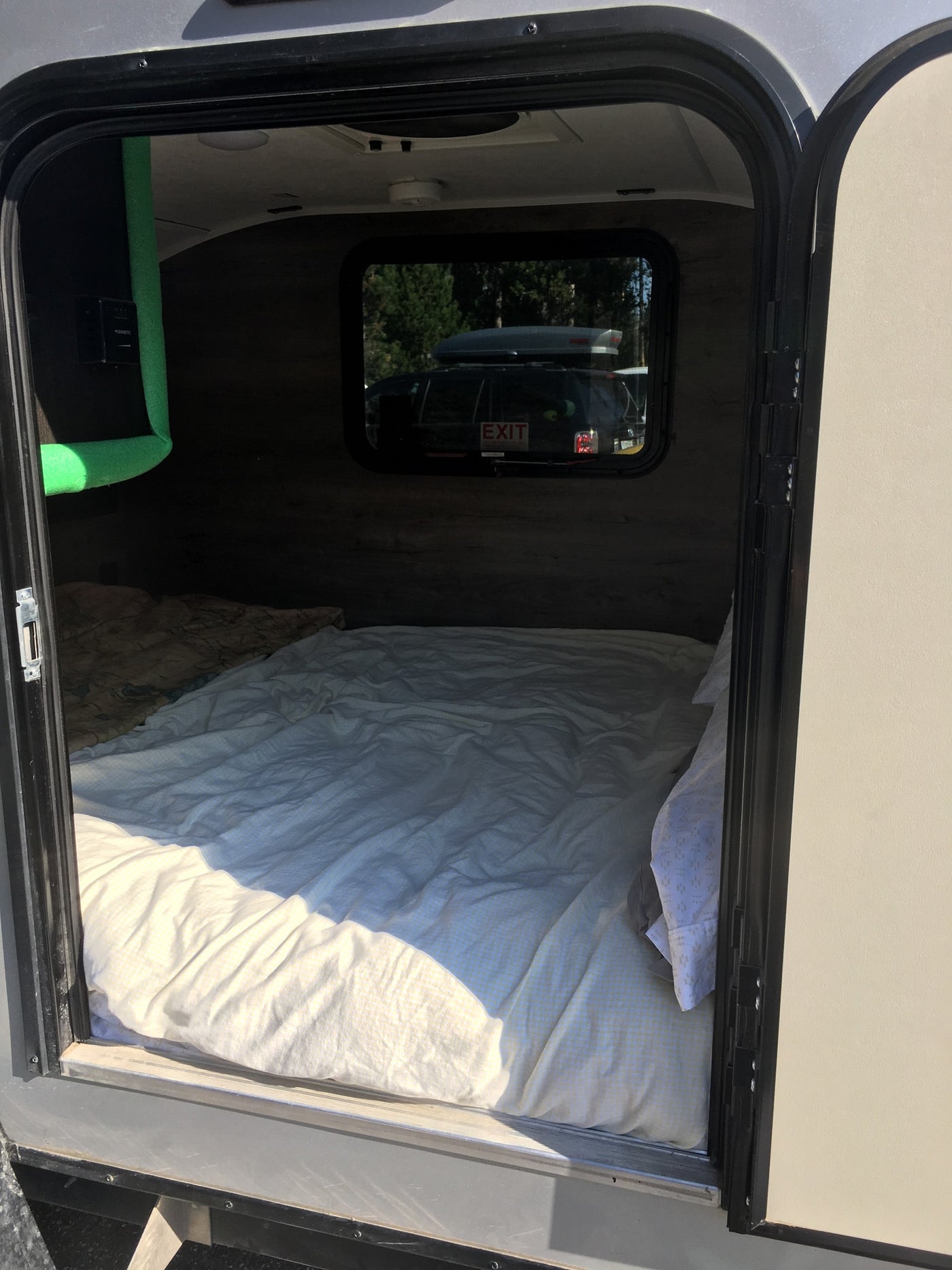 Step inside this cozy RV rental! A comfy bed fills the compact camper interior, seen through the open door. Ready for adventure. — photo 11