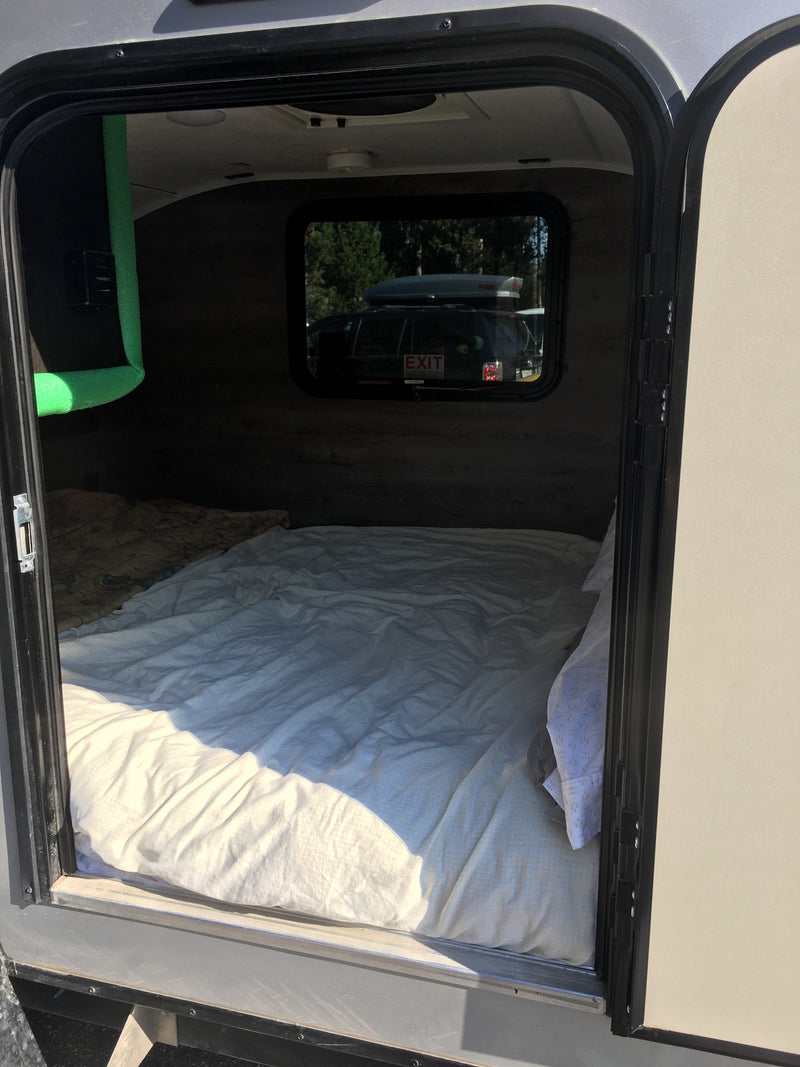 Step inside this cozy RV rental! A comfy bed fills the compact camper interior, seen through the open door. Ready for adventure. — photo 11