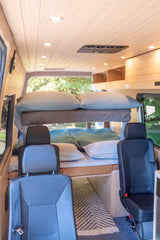 RV rental interior with cozy bunk beds, wood-paneled ceiling lights, and passenger seating. Perfect for families.