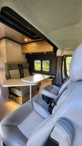 Spacious RV rental interior featuring a light-colored dining table, comfortable bench seating, and wood cabinets.