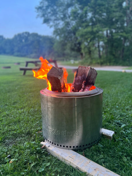 A Solo Stove campfire burns brightly on green grass, ideal for an RV rental getaway. Relaxing outdoor ambiance.