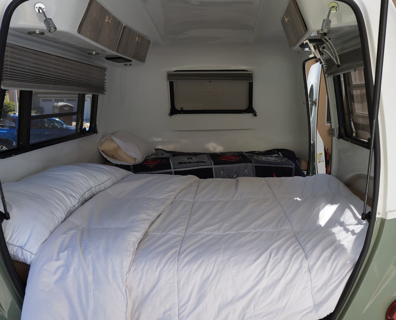 Compact rv rental bedroom with a comfy bed, white duvet, pillows, overhead cabinets, and windows with blinds. Ideal for travel. — photo 5