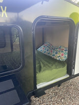 Image shows a compact RV rental's cozy sleeping area with mattress and pillow, ready for travel.