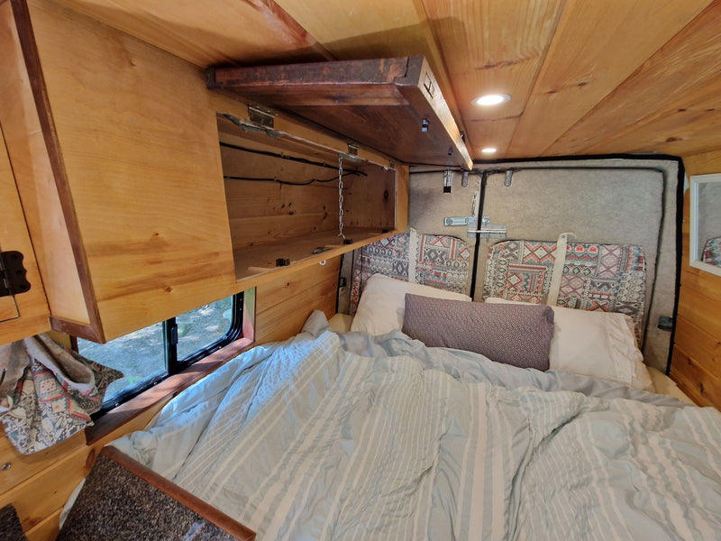  and cushioned bench seating.|Explore this charming RV rental: a wood-paneled camper van interior with a kitchen — photo 4