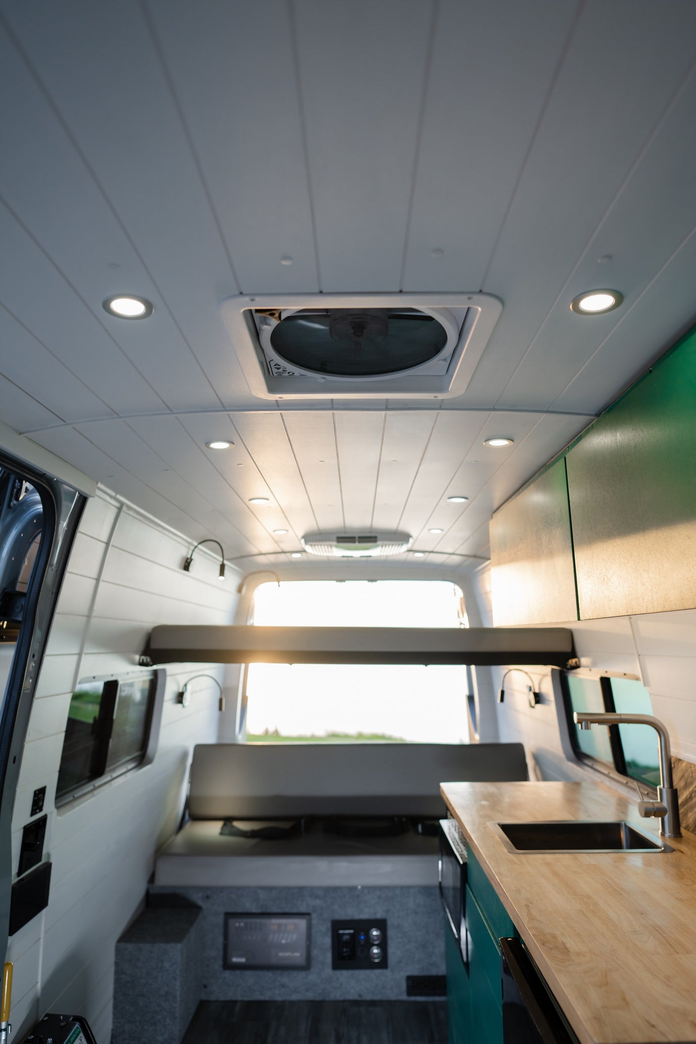 Spacious RV rental interior: cozy bed, modern kitchen, and bright lighting for van life adventures.