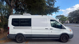 White Ford Transit van, customized with rooftop AC and solar for an rv rental. Ready for adventure.