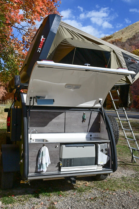 An RV rental rugged camper features an open rear kitchen with sink & fridge, plus a rooftop tent. Perfect for overlanding!