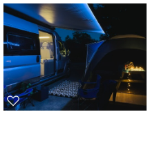 This lit campervan RV rental provides a cozy night camping setup. An extended awning illuminates the campsite with a tent and picnic table.