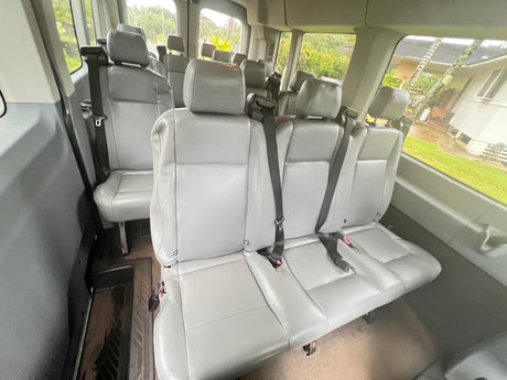 Spacious vehicle interior, often seen in rv rentals, showing multiple rows of grey seats and seatbelts with outside views.
