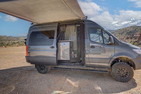 Explore with this gray Sprinter camper van rv rental. Awning out, door open to a kitchen, ready for your next outdoor adventure.