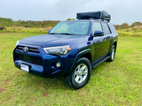 Explore with this blue Toyota 4Runner SUV, featuring a rooftop tent for your next RV rental camping trip.