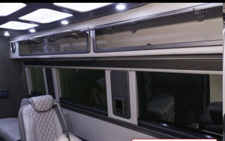 Experience luxury in this RV rental interior: bright overhead lights, glass-front cabinets, and quilted seating for comfort.