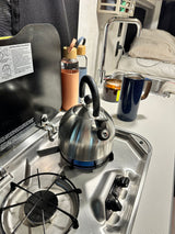 Kettle on the lit stovetop in an RV rental kitchen, ready for a warm beverage.