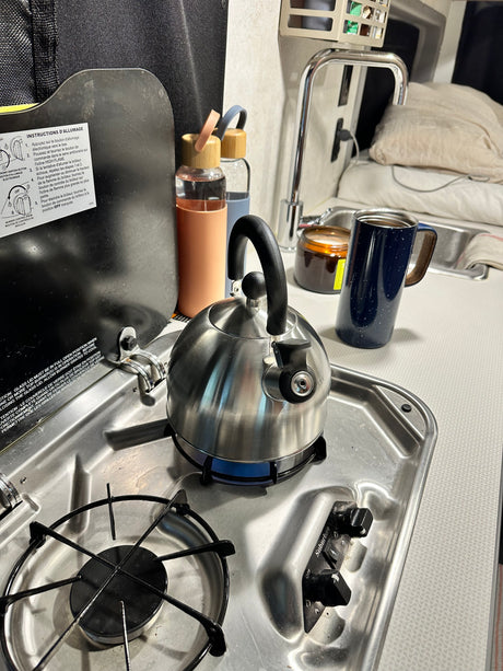 Kettle on the lit stovetop in an RV rental kitchen, ready for a warm beverage.