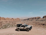 Thrilled traveler atop an adventure truck in vast desert canyons. Experience the freedom of RV rental exploration!