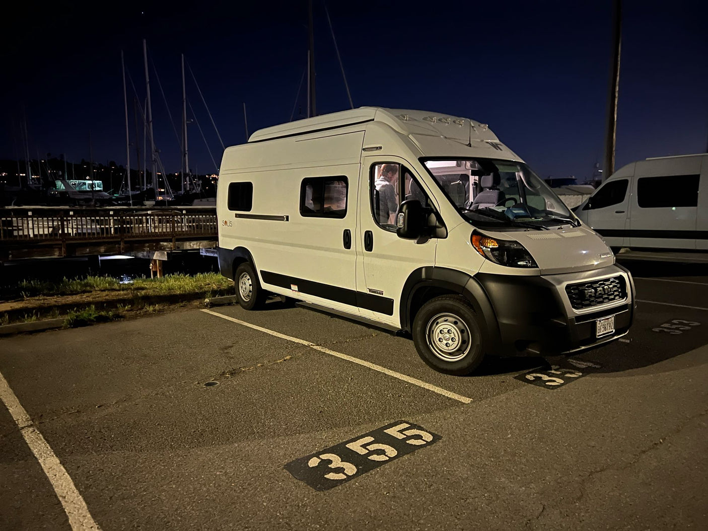 White RV rental van parked at night in a marina lot (spot 355).