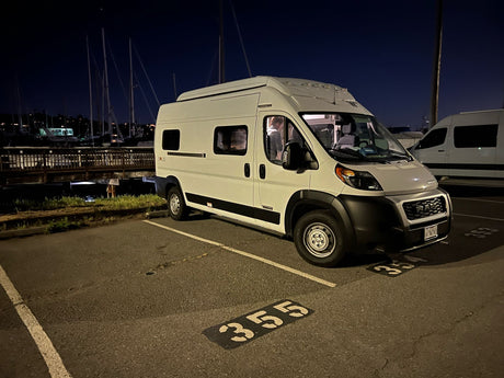 White RV rental van parked at night in a marina lot (spot 355).