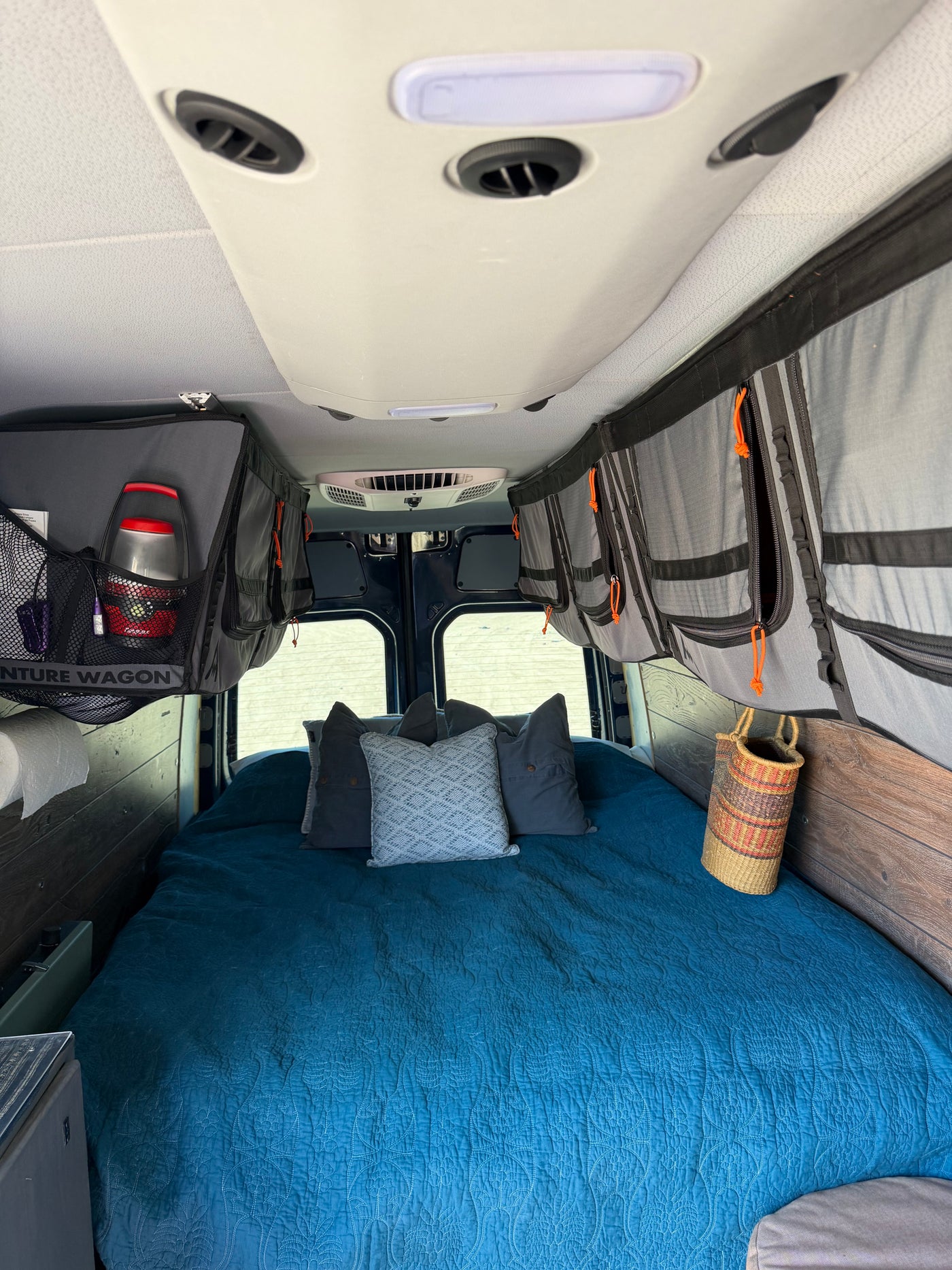 RV rental: cozy bed with blue quilt & pillows, ample overhead storage, and ceiling AC for comfortable travel. — photo 14