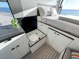 Modern RV rental interior with bed, ample storage, and hidden Dometic toilet, featuring an ocean view.