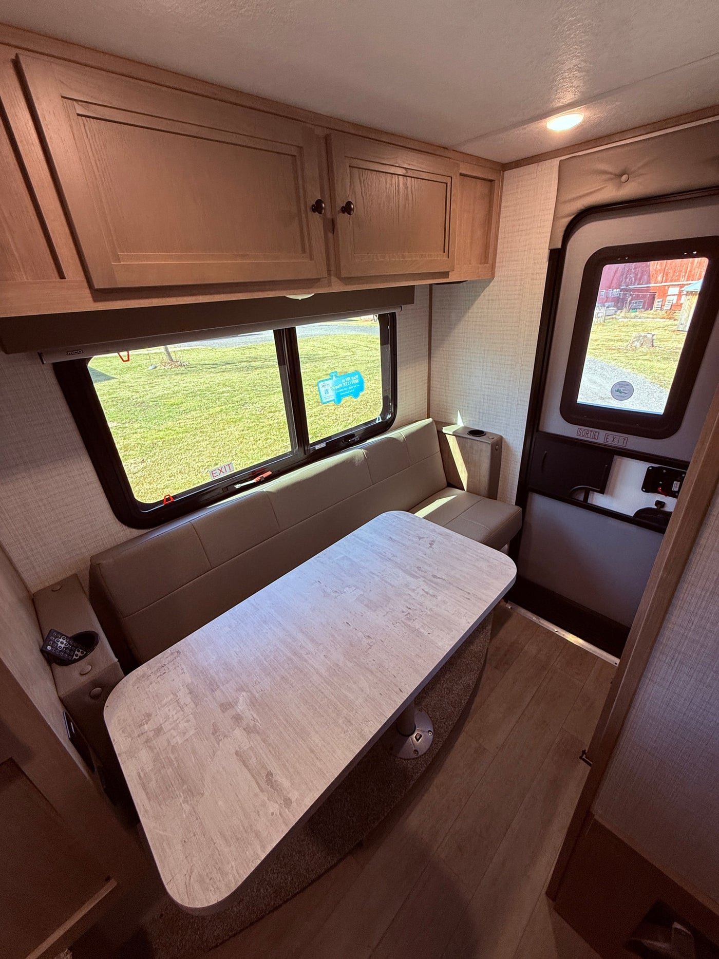 Spacious RV rental interior featuring a bright dinette area with bench seating, overhead cabinets, and large windows. — photo 4