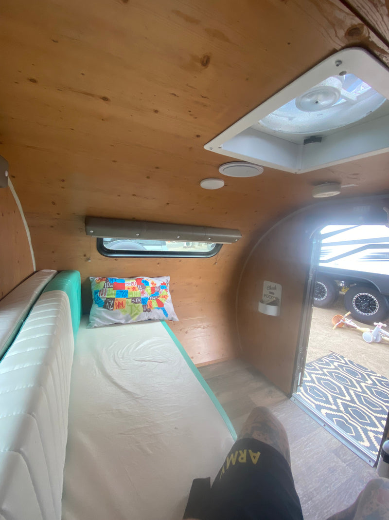 Cozy RV rental interior with a bed, wooden walls, ceiling fan, and an open door revealing an outdoor scene. — photo 10