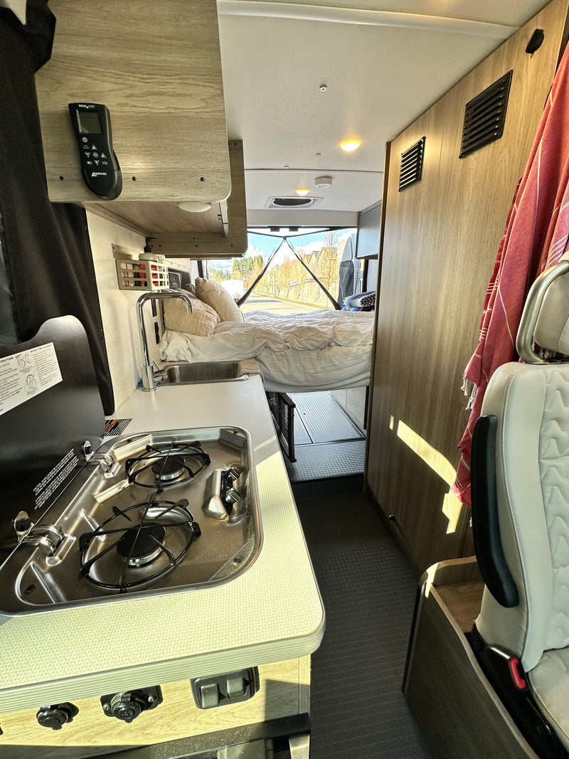 Explore this rv rental's functional interior: compact kitchen, cozy rear bed, and clever storage solutions for your journey. — photo 10