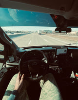 Inside an RV rental van, driving on a highway with the dashboard & wheel visible. Perfect for a sunny road trip!