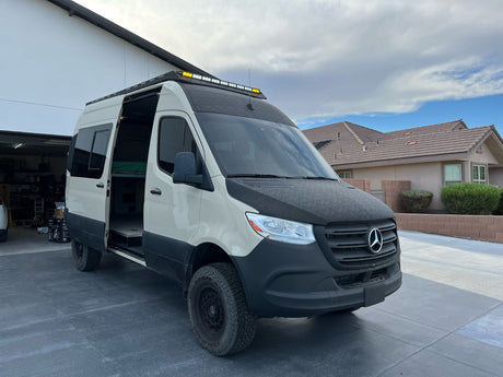 Rugged Mercedes-Benz Sprinter adventure van parked on a driveway with side door open, ideal for an rv rental.
