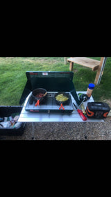 Outdoor cooking setup for an RV rental trip: A portable stove with two pots (meat, potatoes), propane, and camp supplies.