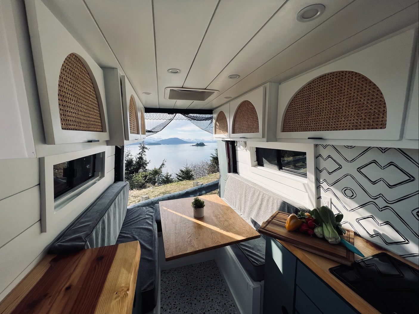 Spacious RV rental interior with a bright dining area, kitchen setup, and panoramic lake views for your travels.
