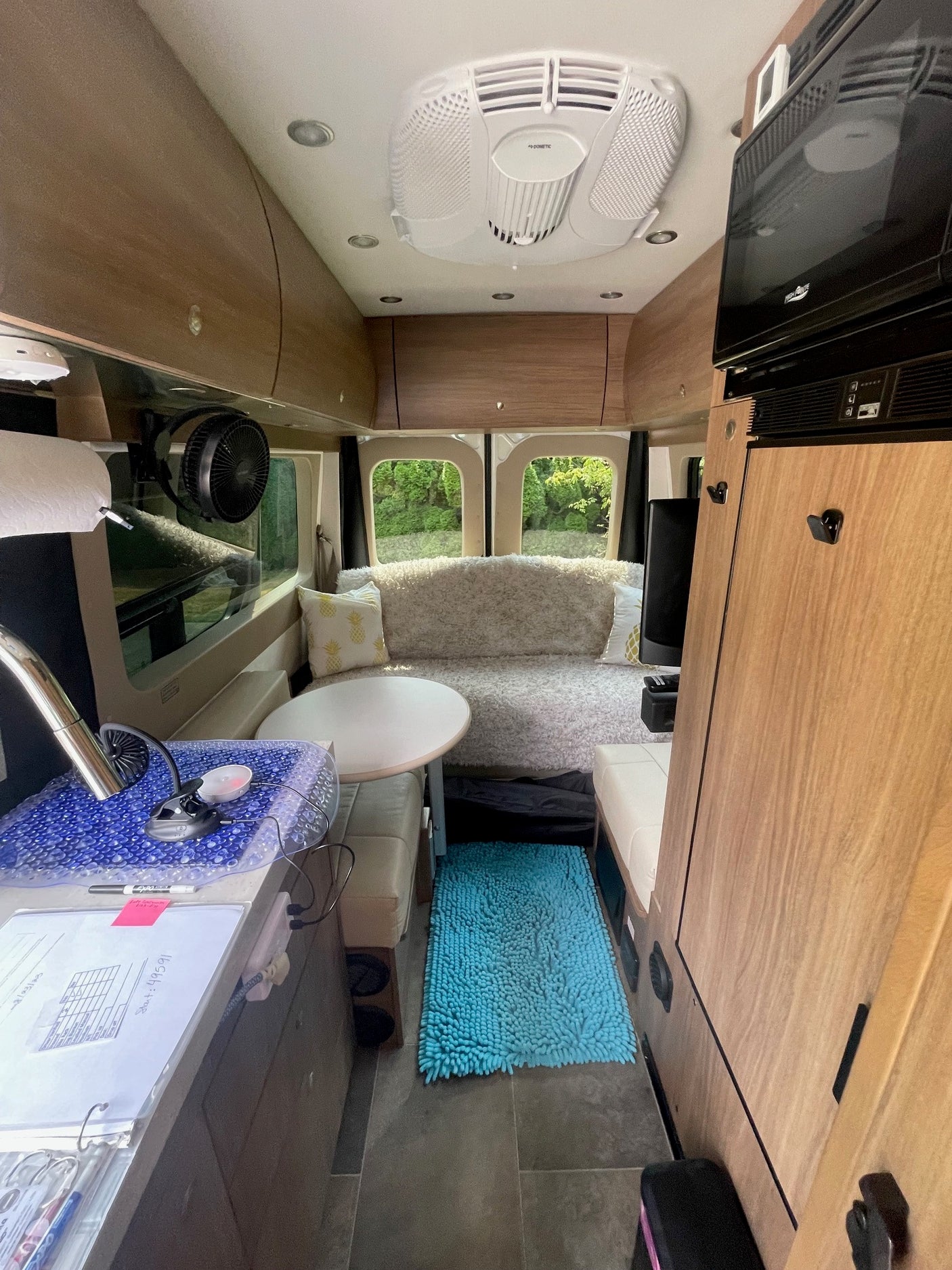 RV rental interior: wood-paneled space with a cozy seating area, kitchen counter, and overhead AC unit for comfort.