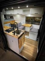 Inside a stylish RV rental: light-filled space with a compact kitchen, seating, and bed for your travels.