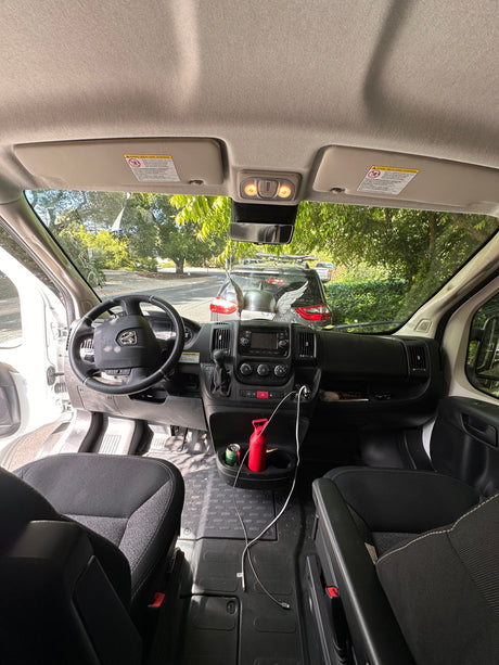 Spacious RV rental van interior, featuring the cockpit, steering wheel, dashboard, and console with charging cables.