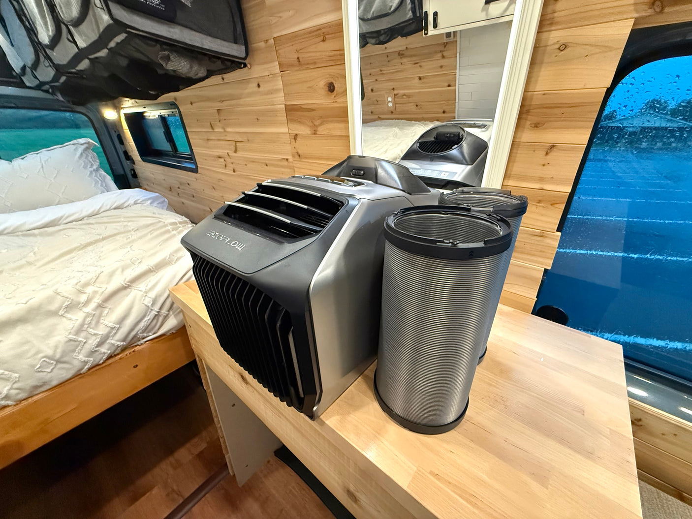 Cooling comfort in an rv rental: Portable EcoFlow AC, ducts, and a cozy bed within a wooden interior.