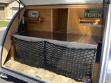 This rv rental teardrop camper features an open galley kitchen with custom signs, storage, and a practical cargo net.
