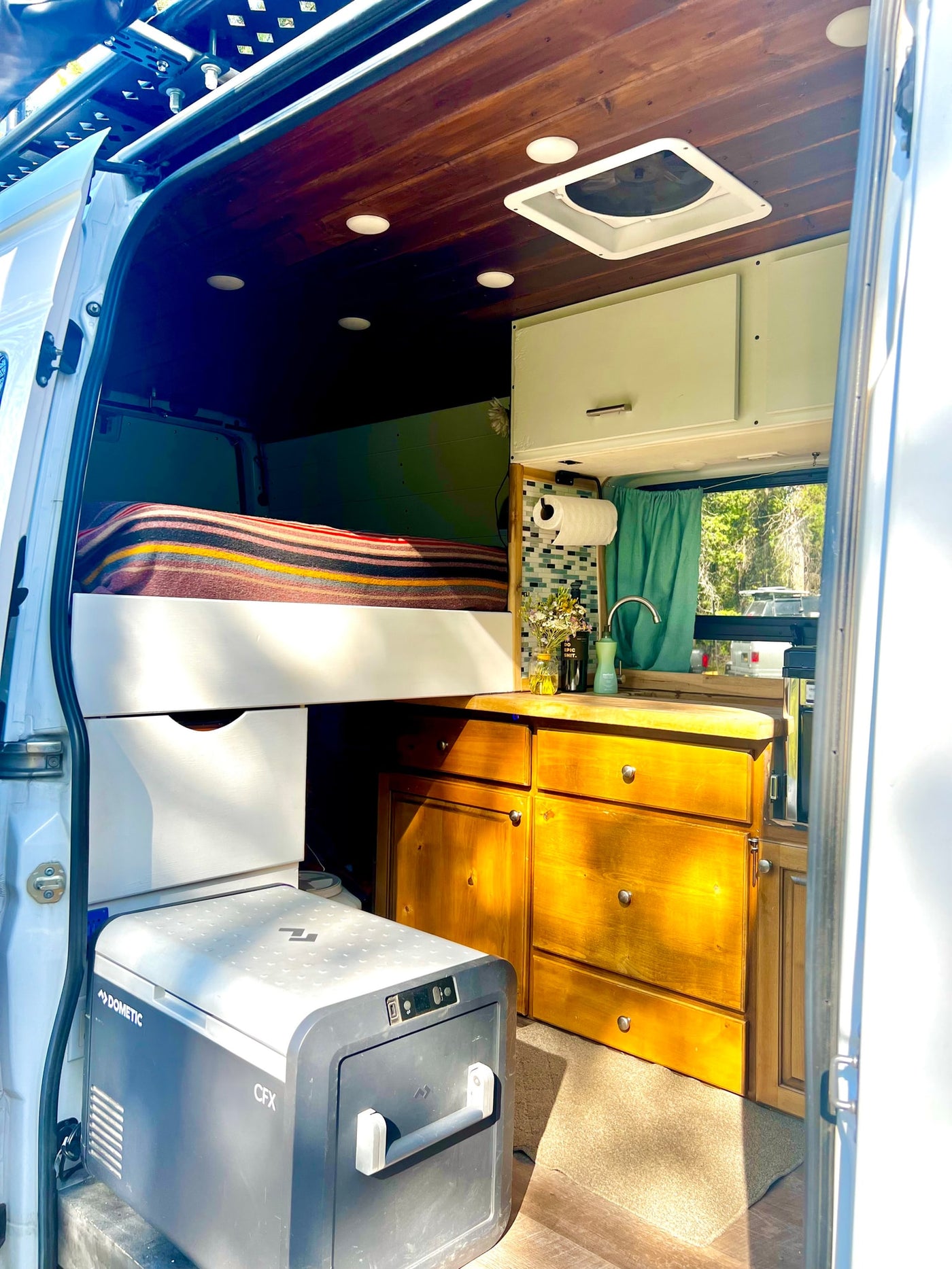 Inside a spacious RV rental camper van: elevated bed, full kitchen, and Dometic fridge. Perfect for mobile adventures. — photo 7