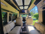 Experience comfort: plush interior of a custom RV rental, featuring cream leather captain's chairs and bench seating.