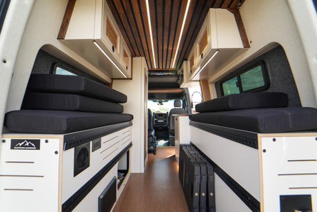 Inside a spacious RV rental campervan: modern interior with wood ceiling, LED lights, and adaptable seating/beds.