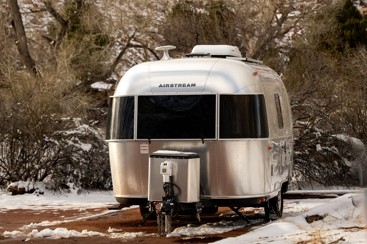  surrounded by desert mountains under a soft twilight sky.|A silver Airstream RV rental parked on snowy ground amidst bare trees. Perfect for winter travel & camping.|Inside an rv rental: a bright