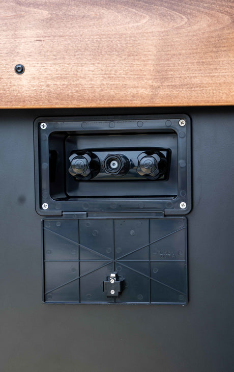 RV rental: Close-up of an exterior utility panel with water hookups and outdoor shower controls.