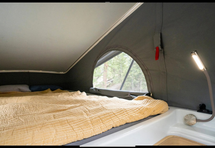  and dining area in a light wood interior.|Cozy RV rental bedroom with a comfy bed and a beautiful forest view through the open rear doors.|Detailed overhead view of an RV rental's interior