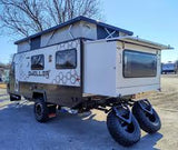 A white and gray Dweller off-road RV, featuring a pop-top and rear spare tires, showcased as an RV rental option.