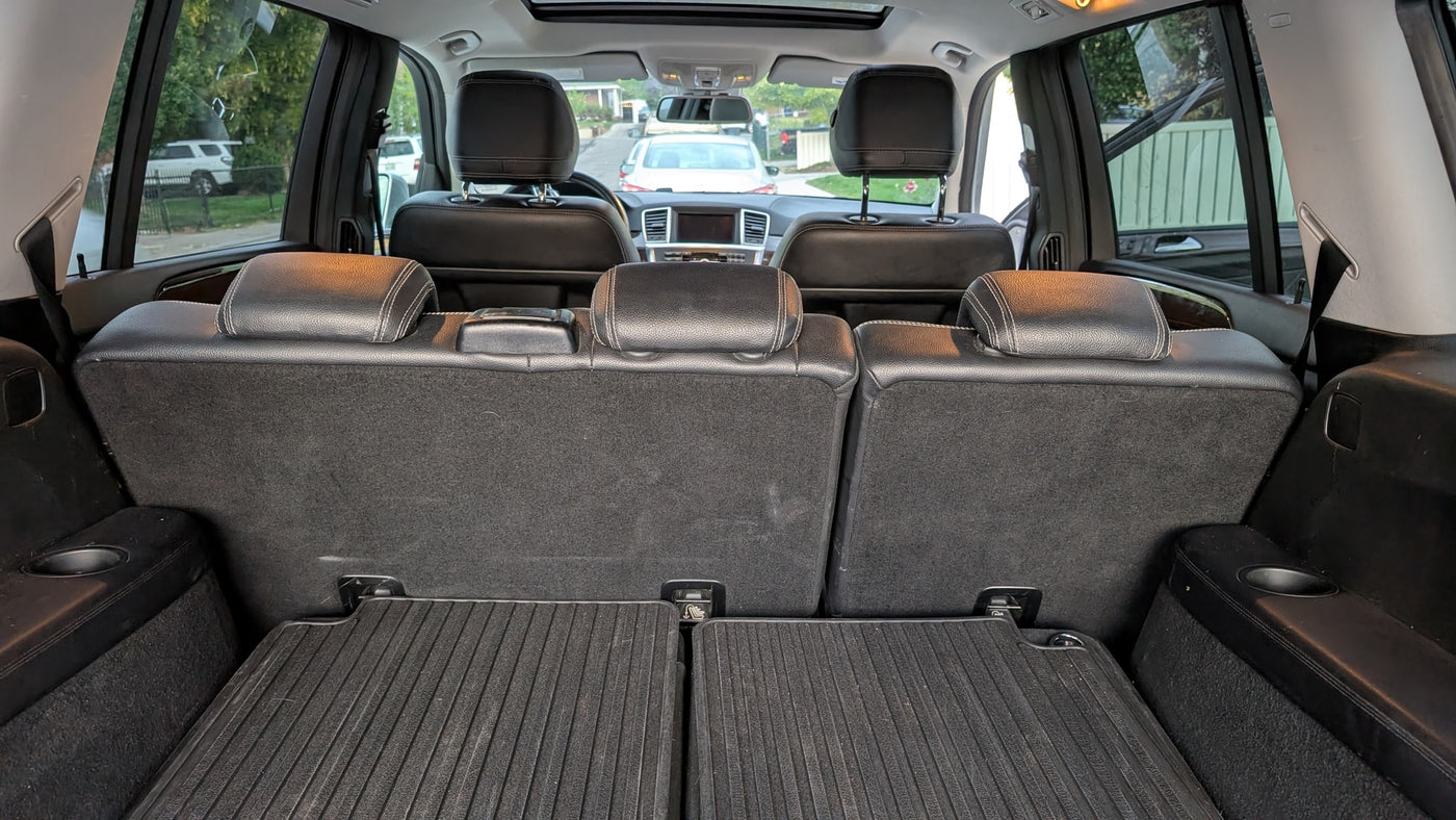 View from SUV trunk: folded third-row seats, rubber mats, and cup holders. Ideal for rv rental travel with ample cargo. — photo 8