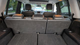 View from SUV trunk: folded third-row seats, rubber mats, and cup holders. Ideal for rv rental travel with ample cargo.
