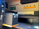 Inside a custom RV rental: Dometic CFX portable fridge, comfy bed, and decor shelf. Ideal for mobile van living adventures.
