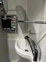 Compact RV rental bathroom with chrome faucet, mirror, multi-dispenser, towel bar, and hook over a small white sink.
